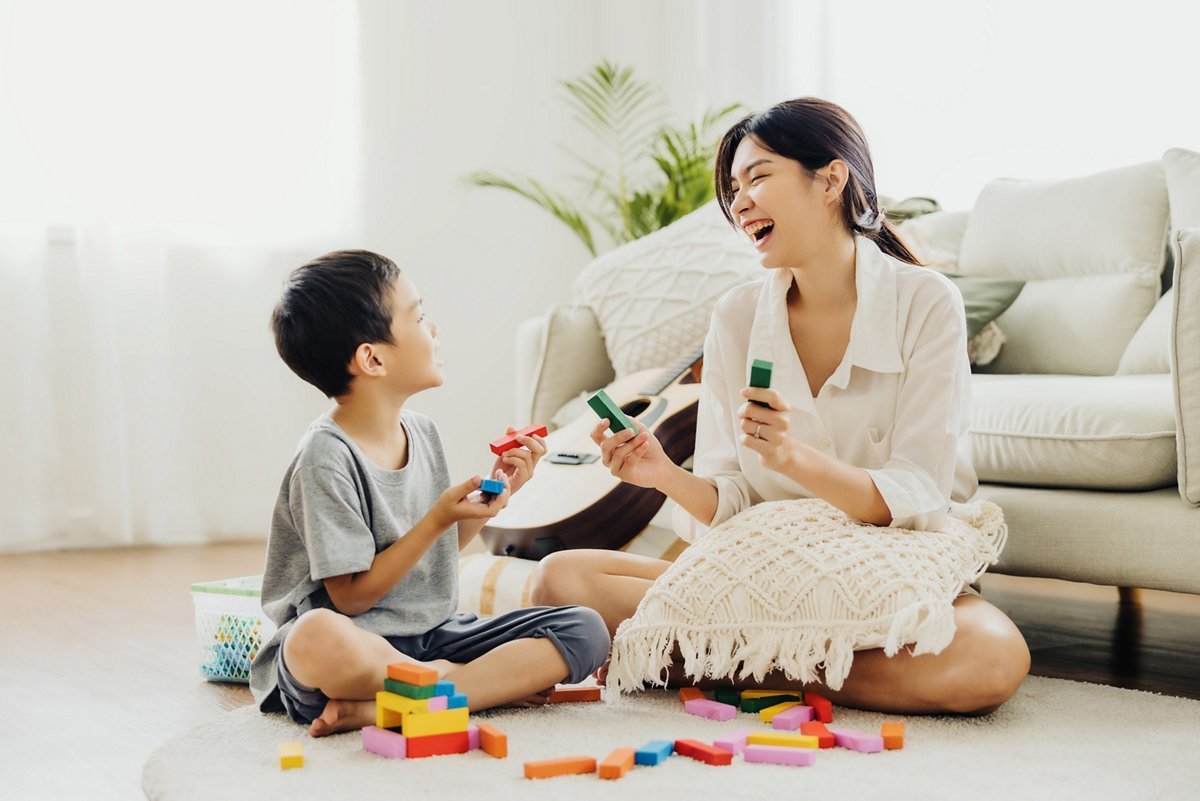 A mother and child smiling while building with colorful blocks